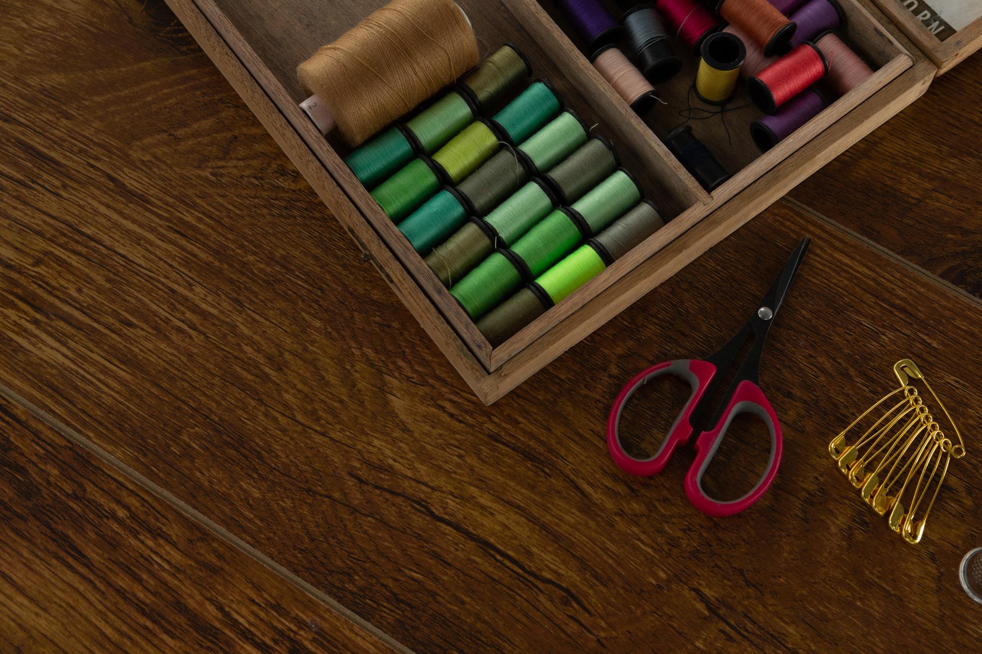 Embroidery samples laid out on a wooden table with threads